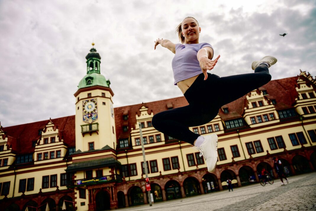 Titelbild Lehrgangsheft 2025 Frau im Sprung vor Gebäude