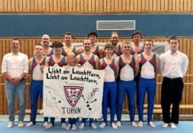 Turnteam des TSV Friedrichsort mit Banner beim Wettkampf, gruppiert in der Sporthalle für ein Teamfoto.