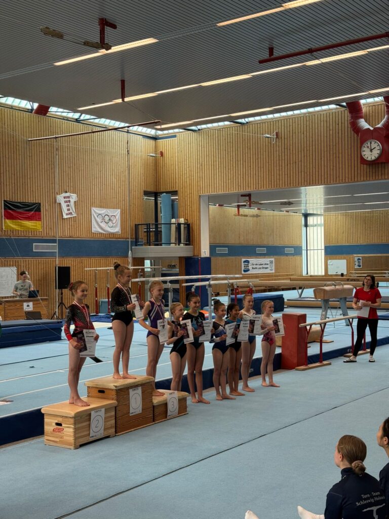 Siegerehrung im Turnen mit Kindern auf dem Podium in einer Sporthalle