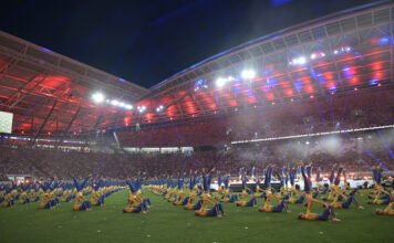 Turner zeigen Akrobatik bei der Stadiongala des Turnfests 2025 im bunt beleuchteten Stadion in Leipzig.