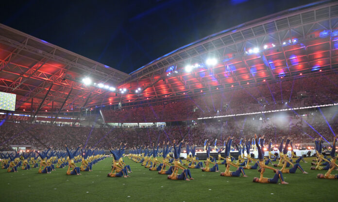 Turner zeigen Akrobatik bei der Stadiongala des Turnfests 2025 im bunt beleuchteten Stadion in Leipzig.