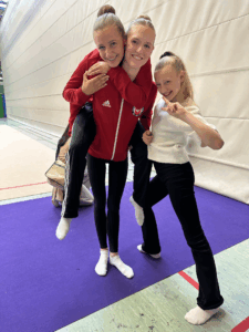 3 Turnerinnen posieren in einer Sporthalle