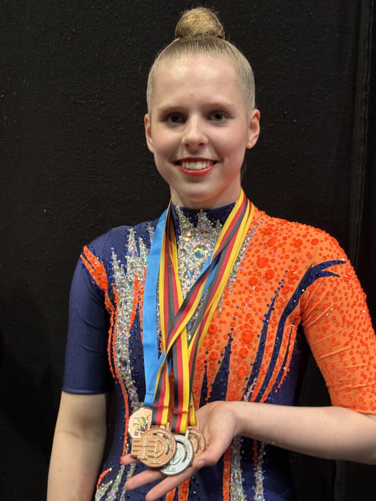 Turnerin posiert mit Medaillen vor schwarzem Hintergrund