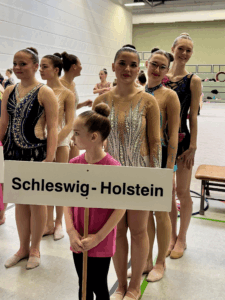 Turnerinnen aufgereiht hinter einem Schleswig-Holstein Schild