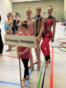 Turnerinnen aufgereiht hinter einem Schleswig-Holstein Schild