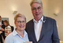 Zwei Personen stehen nebeneinander, eine davon hält ein Geschenk in der Hand.