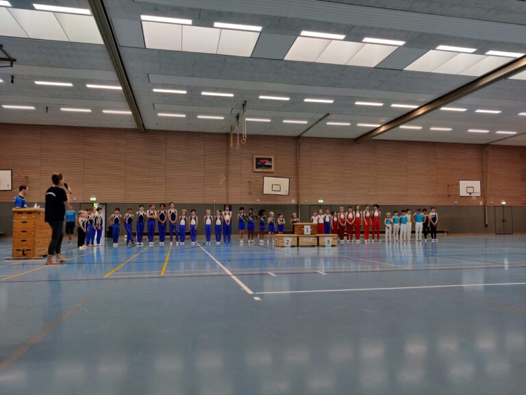 Gruppe von Sportlern in Uniformen steht in einer Turnhalle.