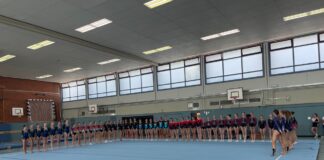 Gruppe von Turnerinnen steht aufgereiht in einer Turnhalle.
