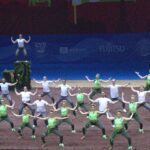 Gruppe bei choreografierter Tanz- oder Gymnastikvorstellung auf einer Bühne.