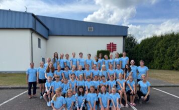 Gruppe in blauen T-Shirts posiert vor einem Gebäude für ein Foto.