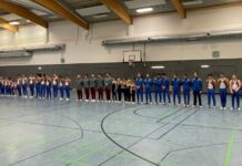 Turner stehen aufgereiht in einer Sporthalle