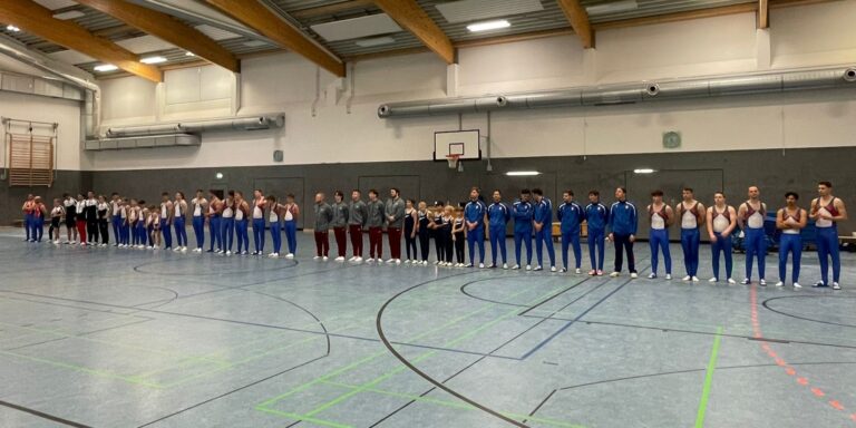 Turner stehen aufgereiht in einer Sporthalle