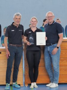 3 Personen vor Turnkasten mit Pokal und Urkunde